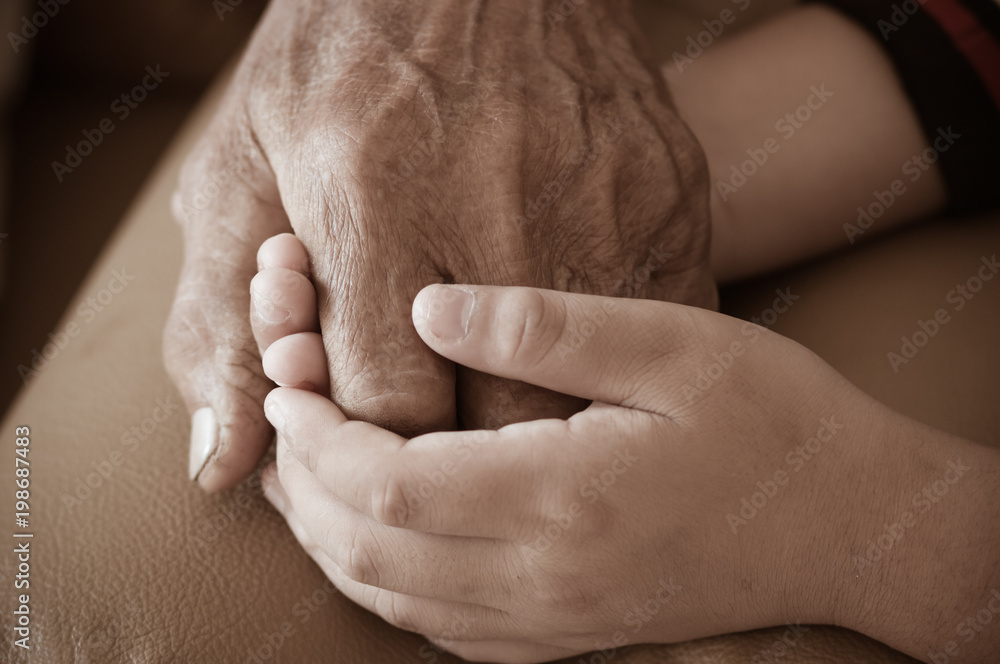 Wall mural Hands of little Asian kids holding poor elderly grandfather man hands wrinkled skin with feeling care and Love. World Kindness Day concept and Adult day care center, Family Older people concept