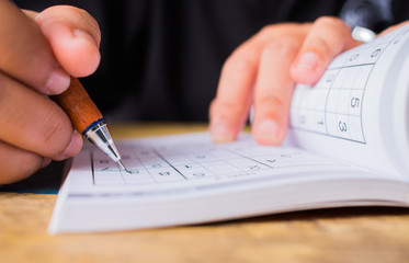 Student is trying solve sudoku with color pencil as hobby at outdoor. Sudoku originally called...