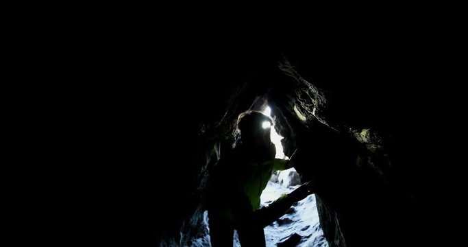 Male hiker exploring a dark cave 