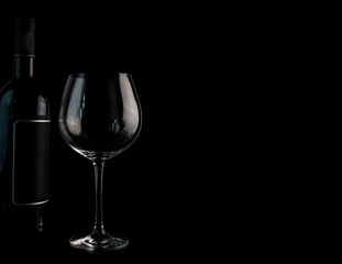 Weinflasche mit einem Weinglas gegen einen schwarzen Hintergrund. Enthält einen Textfreiraum für eigenen Text.