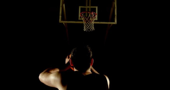 Male basketball player throwing basketball in the basketball hoop 