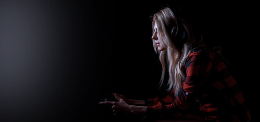 girl gamer in headphones and with a joystick in her hands playing network games preparing to participate in international competitions in e-sports