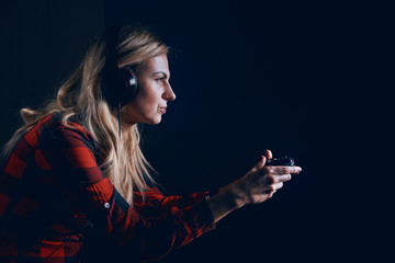 girl gamer in headphones and with a joystick enthusiastically playing on the console © Mykhailovskyi