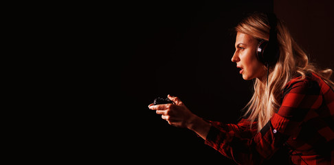 girl gamer in headphones and with a joystick enthusiastically playing on the console