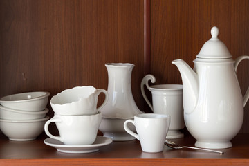 White porcelain tableware for coffee, located on a shelf in the closet. 