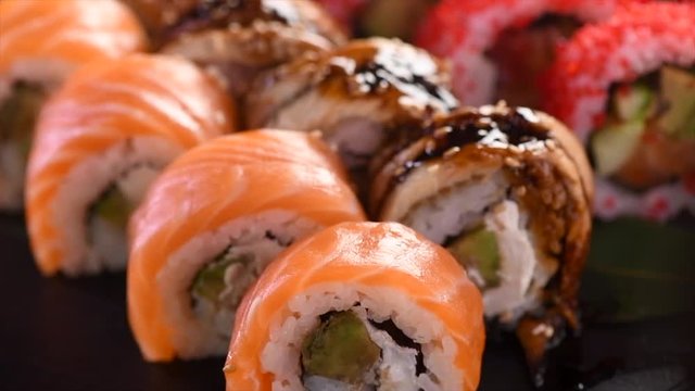 Sushi roll set on black slate background. California set with salmon, tuna, eel, flying fish caviar closeup. Japan restaurant menu. 4K UHD video footage. 3840X2160