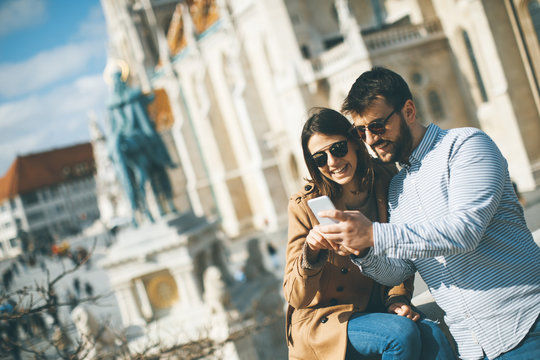 Portrait Of Young Couple Of Tourist In Town Using Mobile Phone