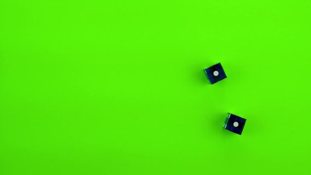 Blue casino dice being rolled and settling on craps (double one) on a green screen. Multiple rolls