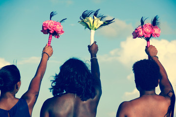 Back of African American women holding colorful bouquets on the air on wedding day. Bride and maids...