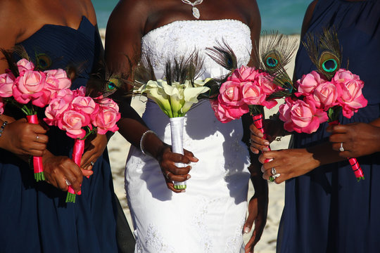 African American bride on white dress together with bridesmaids holding colorful flower bouquets on wedding day outdoors. Glamorous ceremony event closeup. Happiness concept