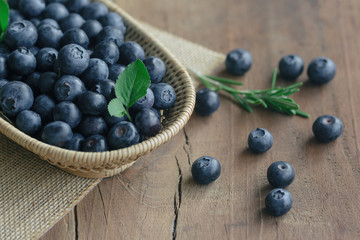 Fresh wild blueberries in wood basket on sack put on wooden table with copy space for background, selective focus. Blueberry is healthy and delicious fruits which have high antioxidant and vitamin C.