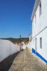 Cozy narrow paved streets with white houses inside the old city walls of Mertola. Beja. Portugal