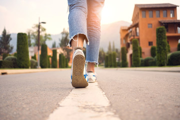 Woman jeans and sneaker shoes on the road go to village with sunset light