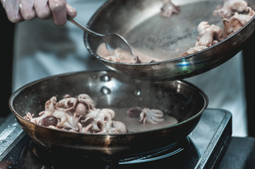 The chef cooks the small octopus on a metal frying pan