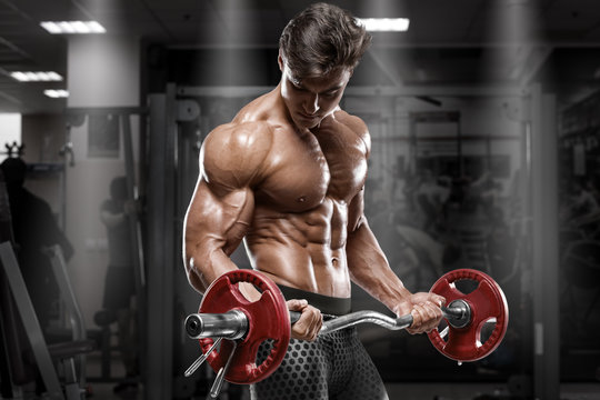 Muscular man working out in gym doing exercises, strong bodybuilder, abs