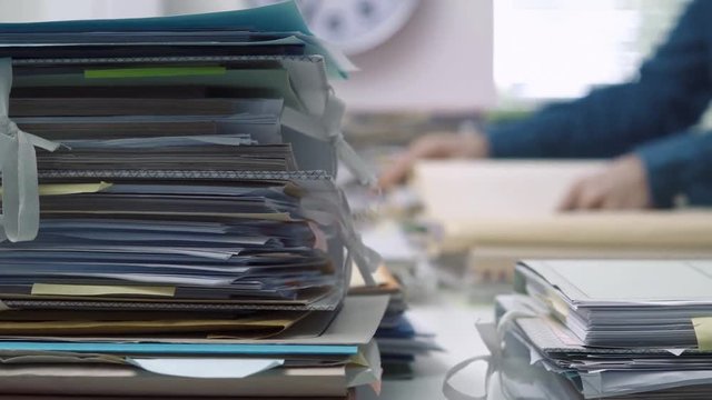 Employee working in the office and piles of paperwork