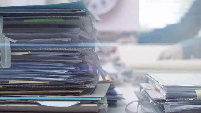 Employee working in the office and piles of paperwork