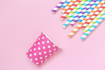 Obraz premium Multicolored drinking straws and paper party cup against rose background minimalistic concept