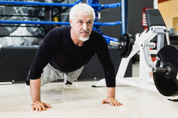 Fototapeta na wymiar Adult gray-haired man doing push-ups