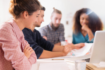 Obraz premium At office. Meeting around a table, a young multiethnic team shar