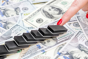 Female hand pushing domino, making domino effect on dollar backgrounds. Business concept.