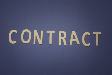 Contract written with wooden letters on a blue background