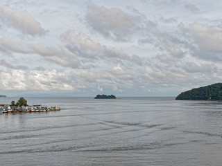 Scenery evening view of Leam Sing estuary or river mouth, where Chanthaburi river meet the sea, with small pier and boat for local fishery and mountain in the background