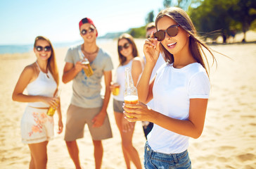 Group of friends hanging out with beer at the beach. Excellent sunny weather. Beautiful figures. Super mood. Summer concept.
