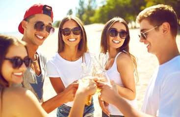 Group of friends hanging out with beer at the beach. Excellent sunny weather. Beautiful figures. Super mood. Summer concept.
