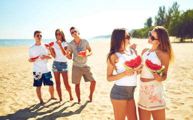 Group of friends having fun eating watermelon. on the beach. Excellent sunny weather. Beautiful figures. Super mood. Summer concept.