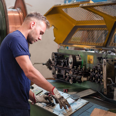 Worker programs the straight-cut-bend machine in a metalworking company.