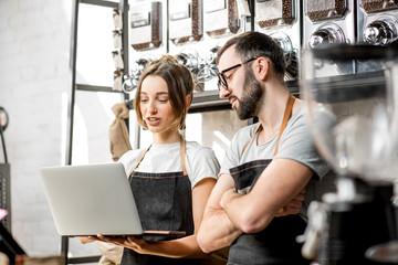 Coffee store owners or managers working with laptop standing at the counter of the shop