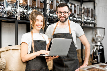 Coffee store owners or managers working with laptop standing at the counter of the shop