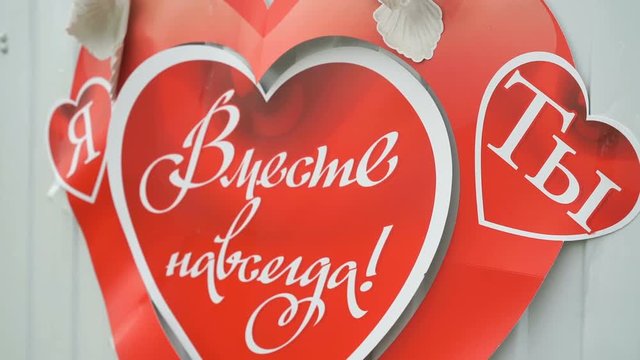 Beautiful poster in view of red heart with inscription in Russian TOGETHER FOREVER YOU hanging at entrance to house. Buyback bride's Russian rite of passage