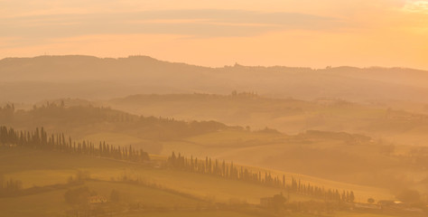 Sunrise in the lands of Tuscany. Warm colors on the hills and haze