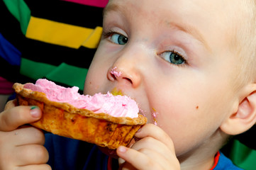 little boy eating a fresh cream cup cake with messy face