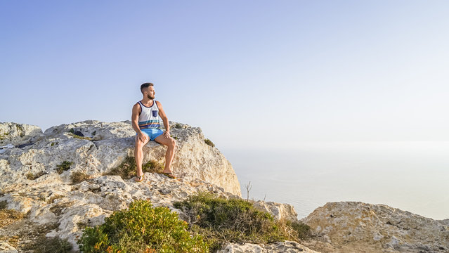 Adult bearded man enjoys beautiful nature view of Malta Dingli cliff. Summer day retreat concept