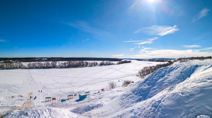 Beautiful ponamara in the winter. The river is covered with ice and snow. Winter landscape. Clear blue sky with clouds. Traces of people in the snow. Footpaths from shoes.