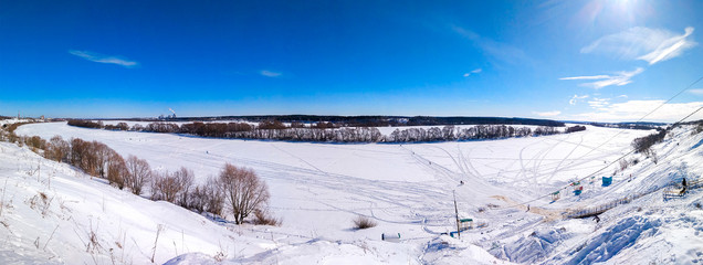 Ponarama winter landscape of nature. The river Oka froze and covered with snow. In nature in winter in Russia. Clear blue sky with clouds. Footprints in the snow from people.