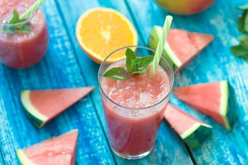 Fresh watermelon and orange smoothie in a glass on a blue wooden rustic background