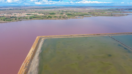 Pink pond in France separated the road from the lagoons for evaporation of salt.