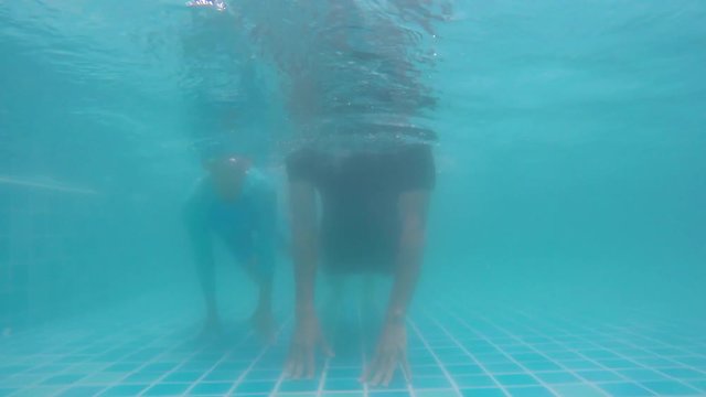 Happy daughter and father swimming underwater in pool