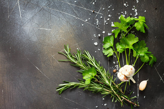 Food background. Parsley and rosemary on a dark stone table. Copy space, top view flat lay background.