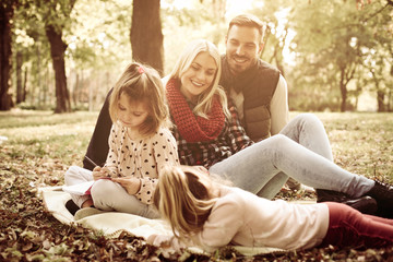 Happy family in park together and little girls coloring book.