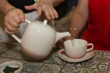 Women's hands pour hot drinks in the cup