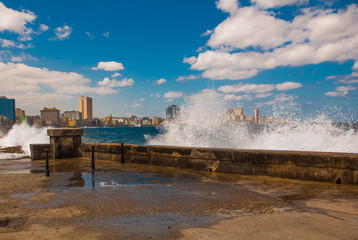 Splashes of waves .View from the Malecon promenade to the city. Cuba. Havana.