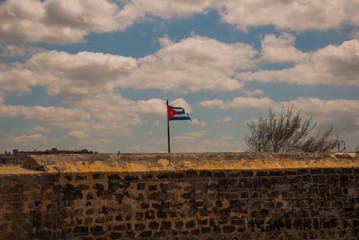 Flag of Cuba against the sky at the fortress wall. The old colonial castle of San Salvador de la Punta. Havana. Cuba