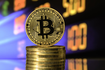 Bitcoin on top of Money stack, against blurry background.