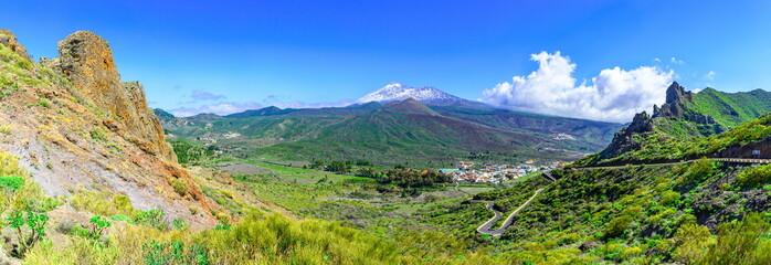 Plakat Tenerife, Canary islands, Spain: Beautiful landscape of a green valley with Teide volcano, covered in snow, in the background.