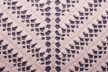 Background of beige wool crocheted shawl pattern on a dark background